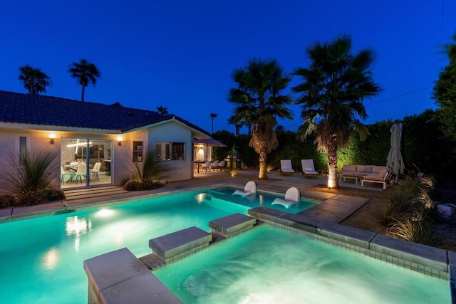 pool at twilight with outdoor lounge area and a patio area