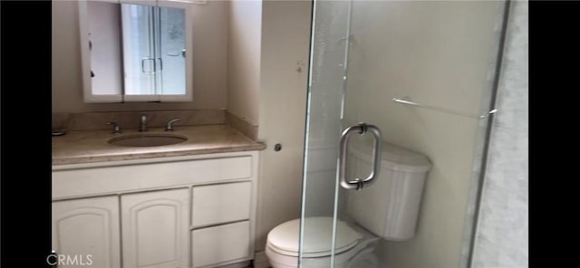 bathroom with vanity, a shower with door, and toilet