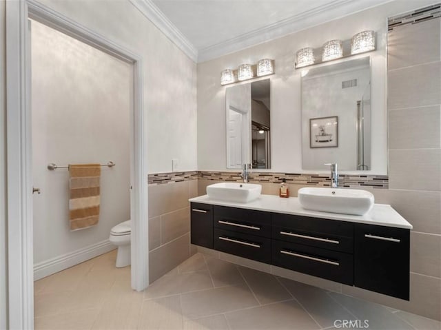 bathroom featuring crown molding, tile patterned flooring, tile walls, vanity, and toilet