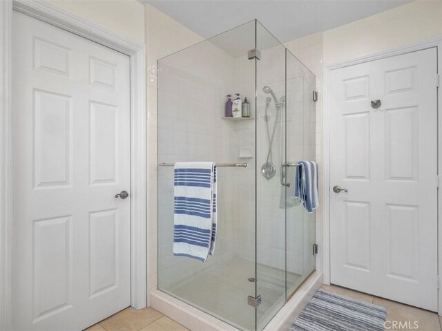 bathroom with an enclosed shower and tile patterned floors