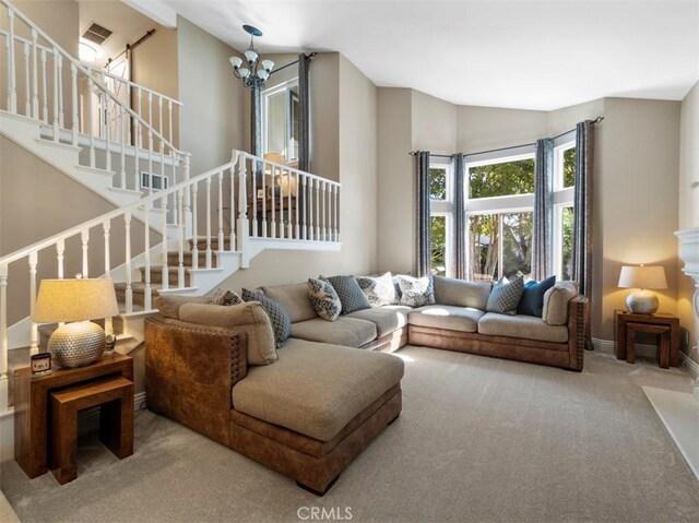 living room with a notable chandelier, high vaulted ceiling, and carpet flooring