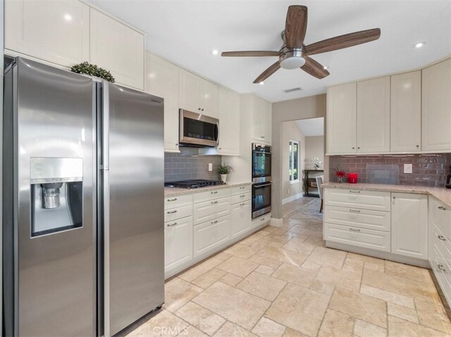 kitchen with backsplash, stainless steel appliances, white cabinets, and ceiling fan