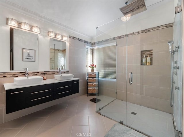 bathroom with a shower with shower door, tile walls, ornamental molding, vanity, and tile patterned flooring