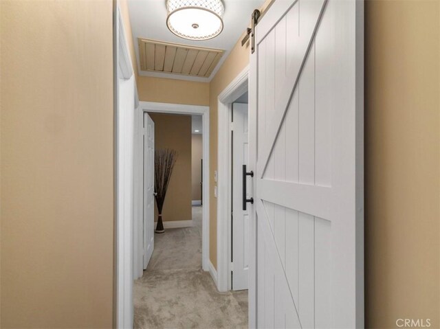 hallway featuring a barn door and light colored carpet