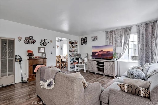 living room featuring hardwood / wood-style flooring, built in features, and ceiling fan