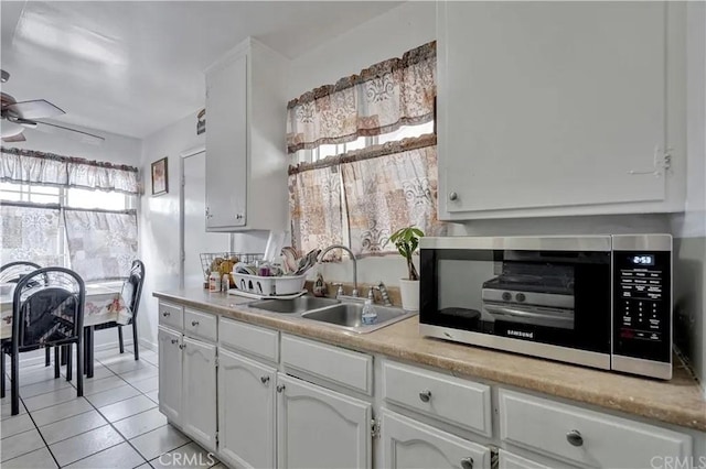 kitchen with sink, light tile patterned floors, white cabinets, and ceiling fan