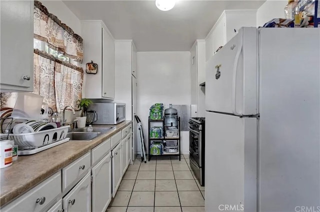 kitchen with white cabinetry, appliances with stainless steel finishes, sink, and light tile patterned floors