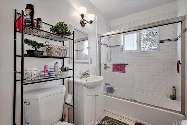 full bathroom featuring tile patterned flooring, vanity, shower / bath combination with glass door, and toilet