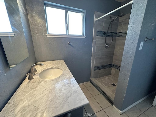 bathroom with a tile shower, vanity, and tile patterned floors