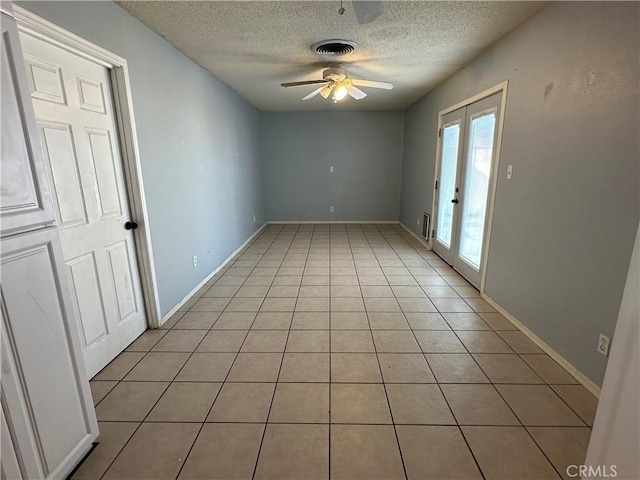 tiled spare room featuring french doors, ceiling fan, and a textured ceiling