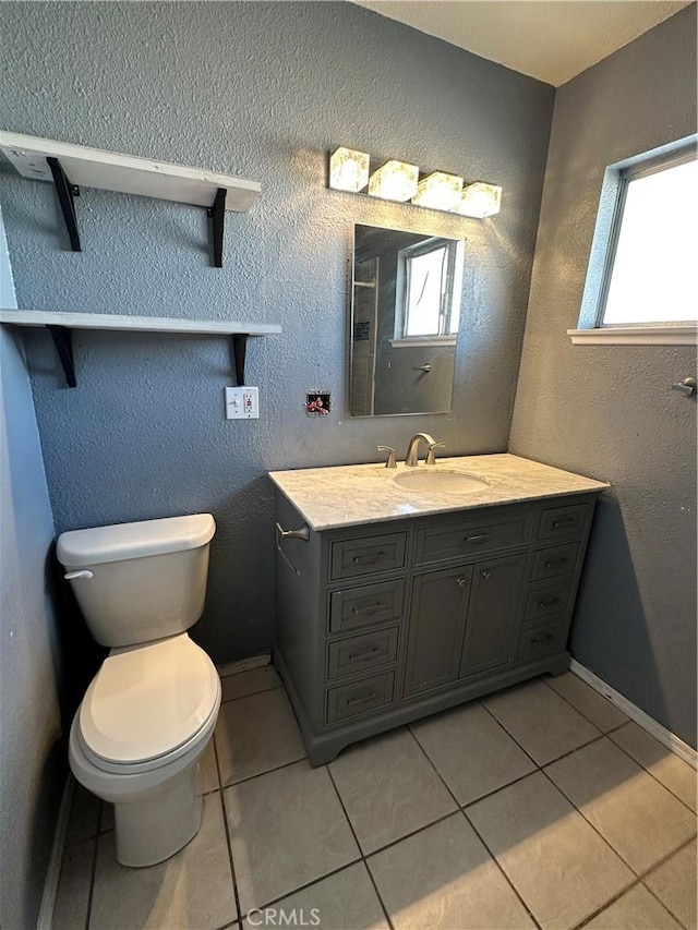 bathroom with vanity, a healthy amount of sunlight, tile patterned floors, and toilet