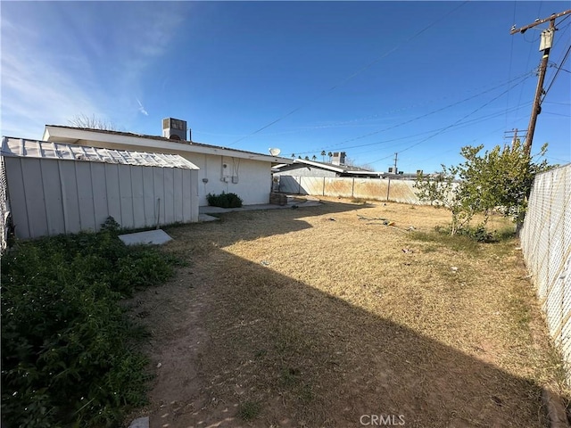 view of yard with central AC and a storage shed