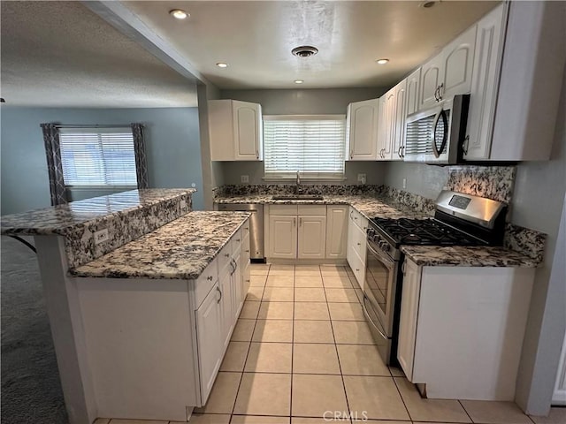 kitchen featuring appliances with stainless steel finishes, sink, white cabinets, and plenty of natural light