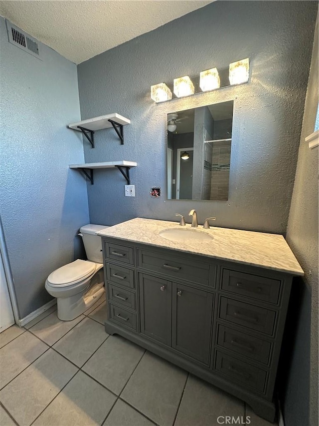bathroom with vanity, walk in shower, toilet, tile patterned floors, and a textured ceiling
