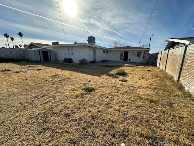 back of house with a storage unit, a lawn, and a patio area