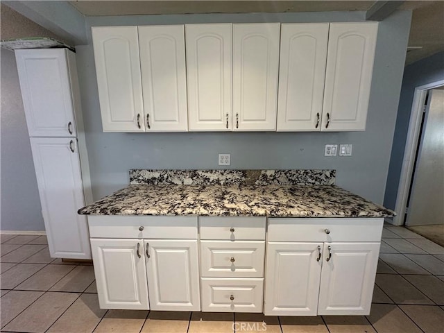 kitchen with light tile patterned floors, white cabinets, and dark stone counters