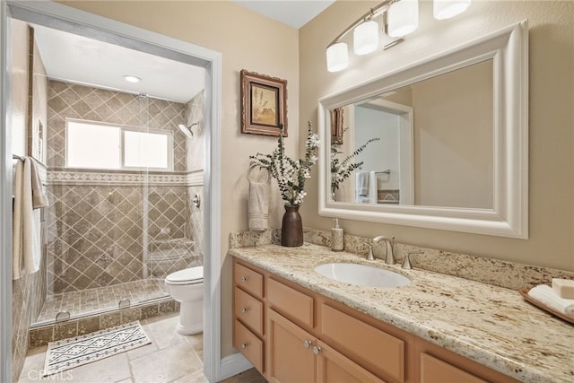 bathroom with tiled shower, vanity, and toilet