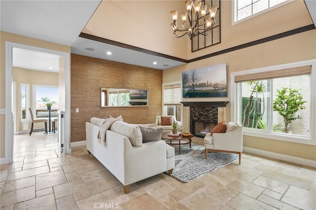 living room with a stone fireplace, plenty of natural light, a chandelier, and a towering ceiling