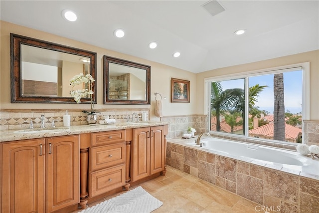 bathroom with vanity, tiled tub, tasteful backsplash, and vaulted ceiling