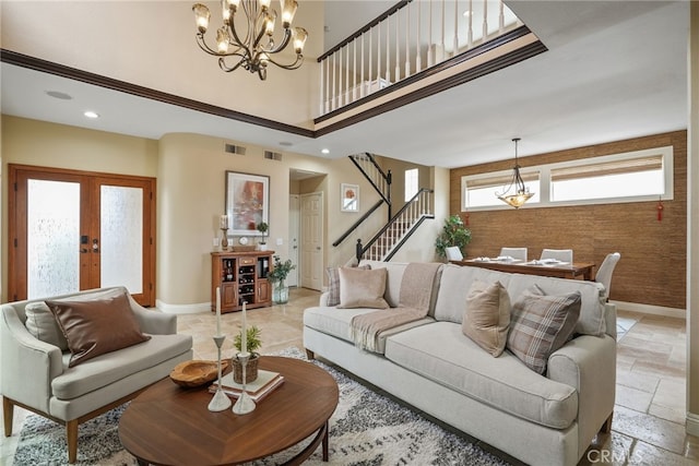 living room with a towering ceiling, french doors, and a chandelier