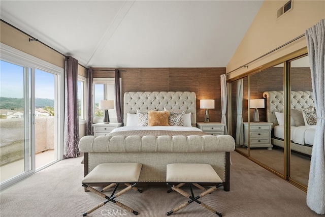 bedroom featuring light colored carpet, lofted ceiling, access to exterior, and a closet