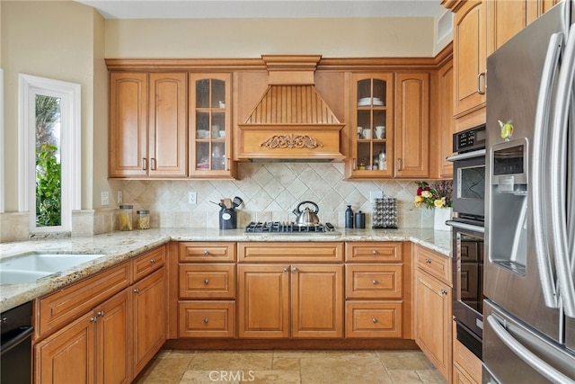 kitchen featuring premium range hood, stainless steel appliances, light stone countertops, and backsplash