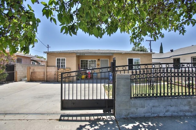 view of front facade featuring a fenced front yard, a gate, and stucco siding