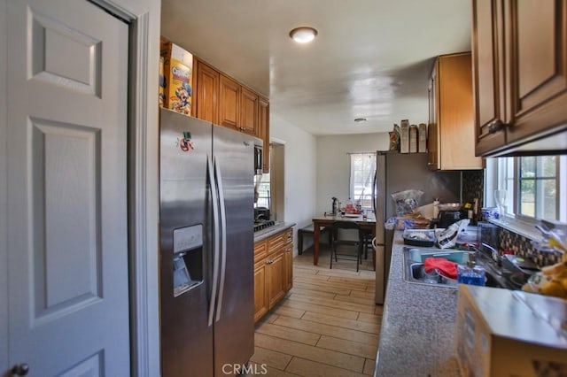 kitchen featuring light wood finished floors, plenty of natural light, stainless steel fridge, and brown cabinets