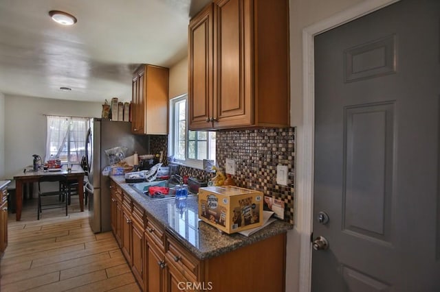 kitchen with tasteful backsplash, brown cabinetry, a sink, and light wood-style floors