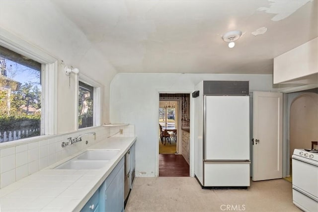 kitchen featuring sink, white stove, a wealth of natural light, paneled built in fridge, and decorative backsplash