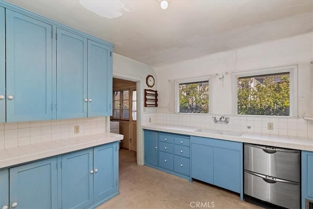 kitchen featuring sink, decorative backsplash, blue cabinetry, and stainless steel dishwasher