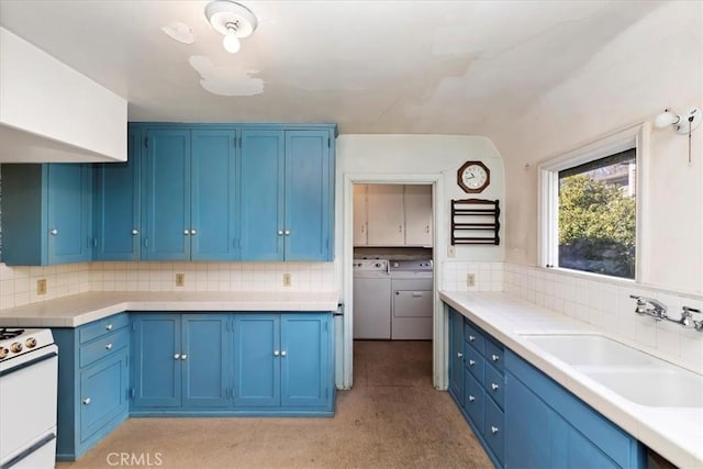 kitchen featuring sink, range, backsplash, blue cabinets, and separate washer and dryer