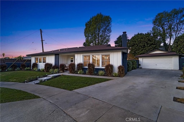 ranch-style home featuring a garage, an outdoor structure, and a lawn