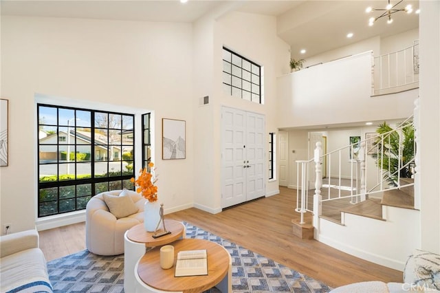 living room featuring an inviting chandelier, hardwood / wood-style floors, and a towering ceiling