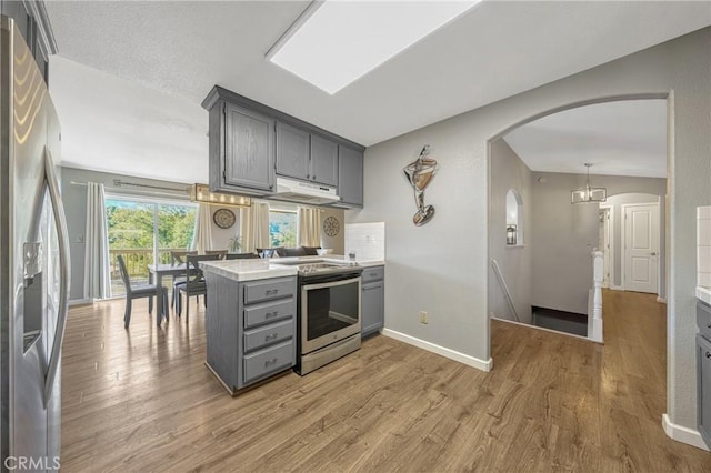 kitchen featuring stainless steel appliances, kitchen peninsula, hardwood / wood-style floors, and gray cabinetry