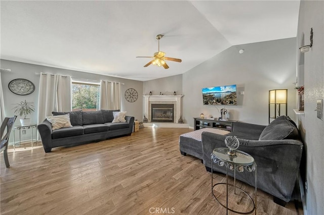 living room featuring ceiling fan, lofted ceiling, and light wood-type flooring