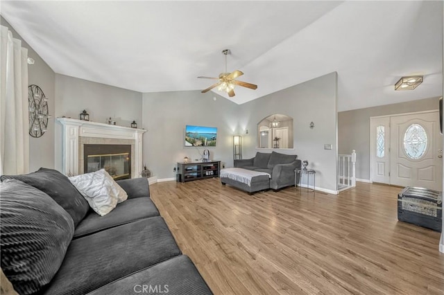 living room featuring hardwood / wood-style flooring, ceiling fan, lofted ceiling, and a fireplace