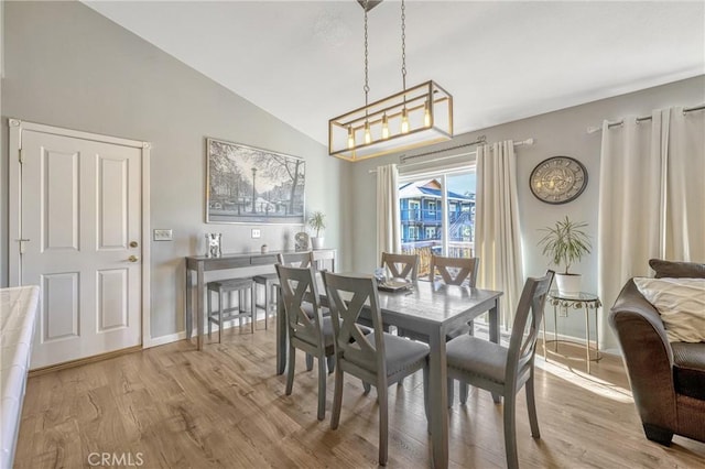 dining room with vaulted ceiling and light hardwood / wood-style flooring