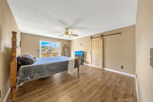 bedroom featuring hardwood / wood-style flooring, ceiling fan, a barn door, and access to exterior