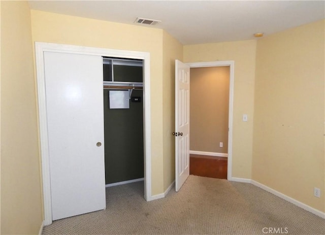 unfurnished bedroom with light colored carpet and a closet