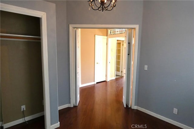 hallway with dark hardwood / wood-style flooring and a notable chandelier