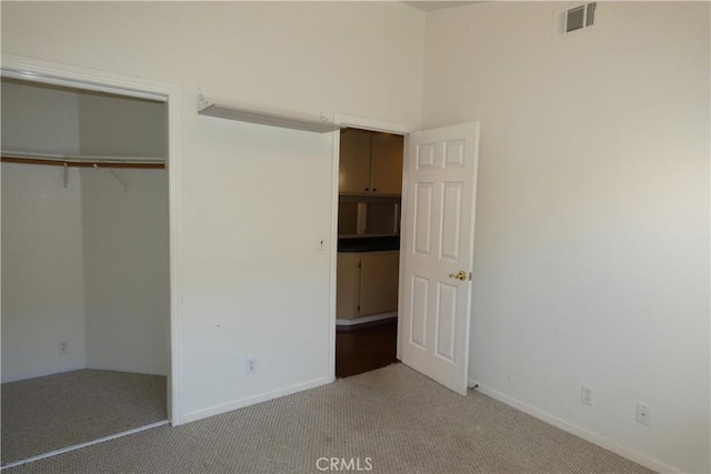 unfurnished bedroom featuring light carpet and a closet