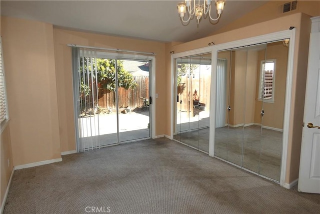 entryway featuring an inviting chandelier, carpet floors, and vaulted ceiling