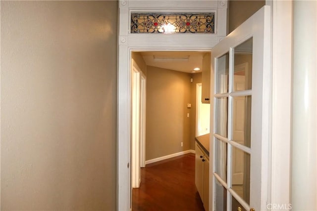 corridor featuring dark wood-type flooring and baseboards