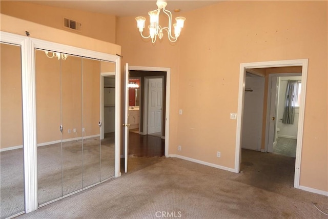 unfurnished bedroom featuring high vaulted ceiling, a closet, a chandelier, and carpet flooring