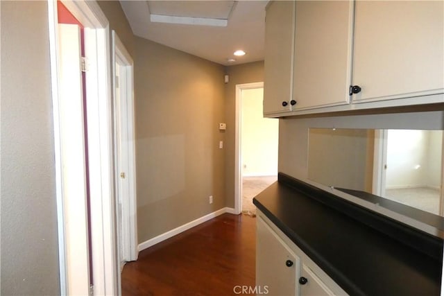 hallway with dark wood finished floors, recessed lighting, and baseboards