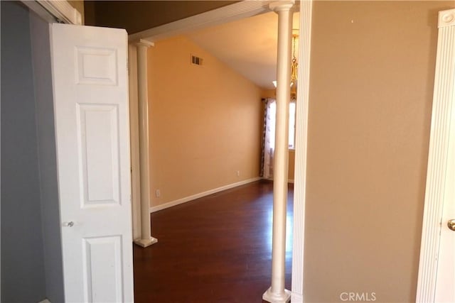 corridor with visible vents, baseboards, lofted ceiling, decorative columns, and wood finished floors