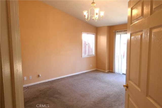 carpeted spare room featuring a chandelier and vaulted ceiling