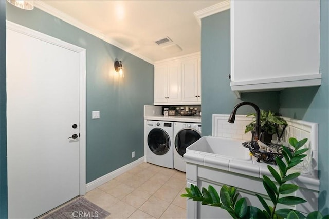 washroom with sink, crown molding, light tile patterned floors, washing machine and dryer, and cabinets