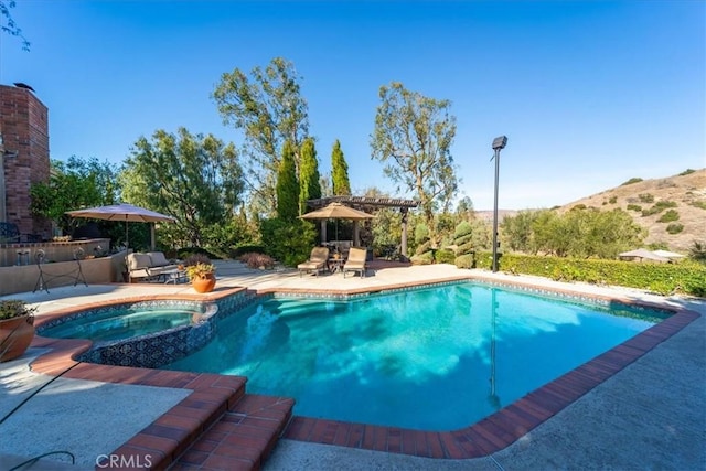 view of swimming pool with an in ground hot tub, a patio area, and a pergola